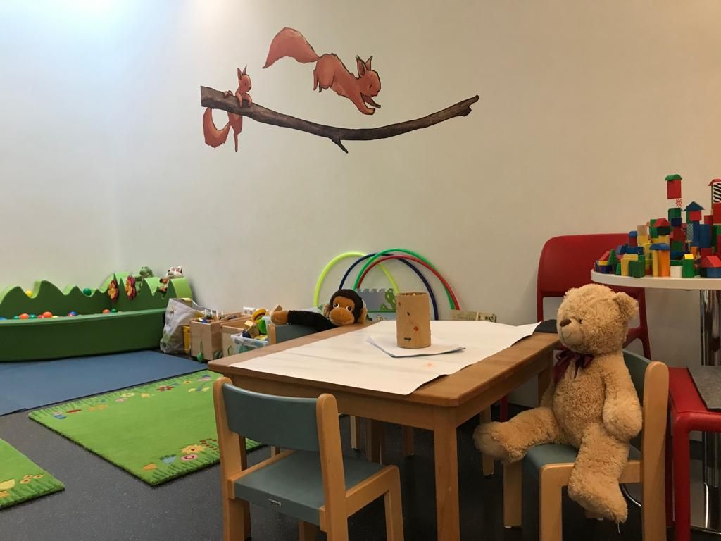 Kinderraum mit Tisch, zahlreichen Spielgeräten und Spielsachen